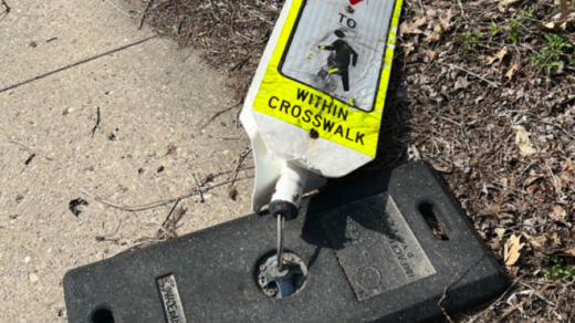 A pedestrian crossing sign was recently run over by a speeding car at Greenfield Ave. and Kaercher St., illustrating the need for better safety infrastructure.